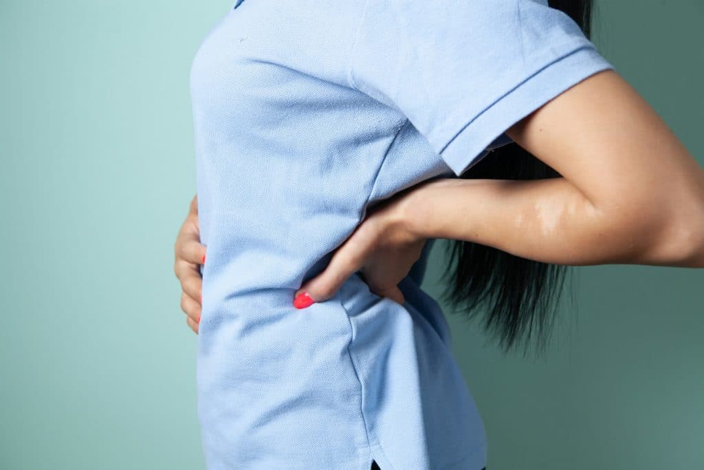 Kvinde med hånd på lænden i stille øjeblik — smertehåndtering med hypnose